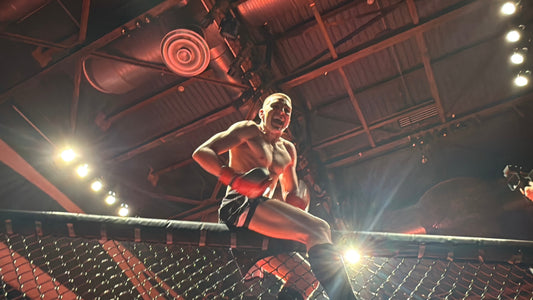Connor Brennan sitting on top of the cage after his win. 